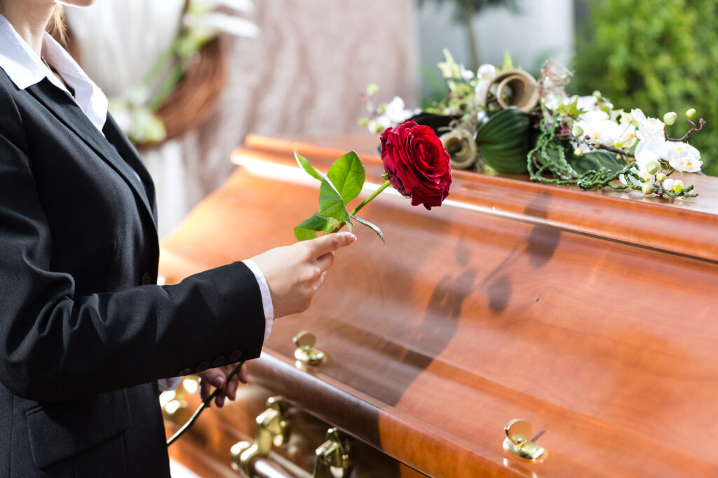 Women places rose on a casket of loved one who died from a wrongful death accident. 